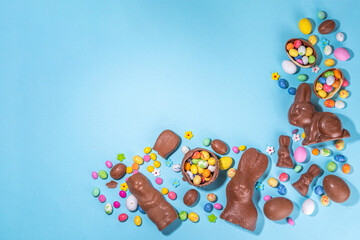 Easter chocolate egg and bunny background. High-colored flat lay with chocolate bunny and rabbits, colorful chocolate eggs. Preparation for Easter, greeting card, Easter sale, top view copy space