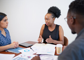 Black woman executive discusses financial results around boardroom office table