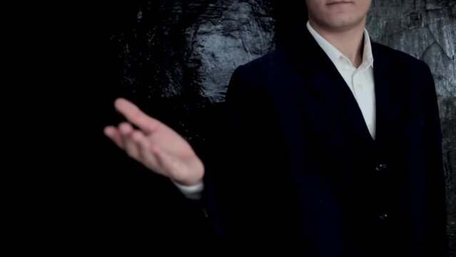 Faceless shot of a young teenager in a business outfit expressing hand gestures on black background.
