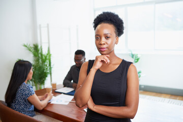Portrait of serious young Black business woman hand to chin in boardroom