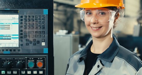 Process engineer woman in helmet, goggles, pointing and touching dashboard buttons at manufacturing factory, young beautiful woman working in industry