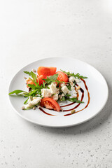 Healhy salad with arugula, cherry tomatoes and feta cheese on white textured background. Green diet vegetarian salad concept with copy space