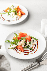 Green salad with arugula, cherry tomatoes and feta cheese with cutlery on white background. Healthy diet vegetarian salad concept
