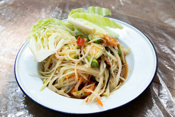 Thai papaya salad (Somtum) in white plate on wooden table