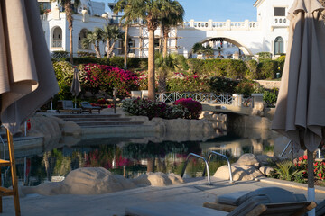 Egyptian garden with palm trees in the hotel. Swimming pool and accommodation in a tropical resort. Buildings, swimming pools and a recreation area near the Red Sea. Egypt