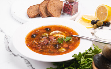 Tomato soup with olives and sausages in a white plate