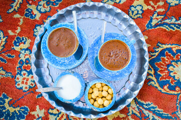 Yazd, Iran - 1st june, 2022: Persian coffee set up for two on beautiful decorated silver plate; blue cups and bowl of candies and sugar