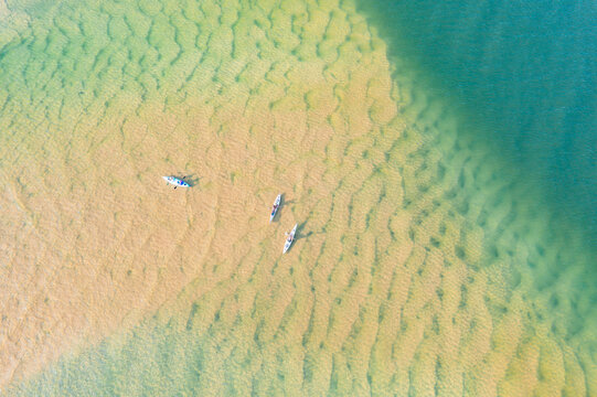 Aerial view of kayaks amongst tidal sandbars and blue water - Powered by Adobe