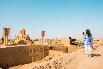 Scenic Kashan rooftop panorama with wind-catchers and tourist in hot summer day