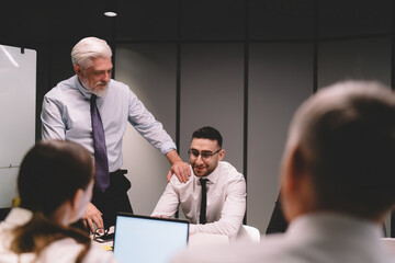 Male director touching shoulder of employee during meeting in boardroom