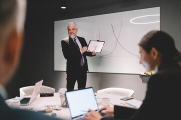 Cheerful businessman explaining chart to colleagues