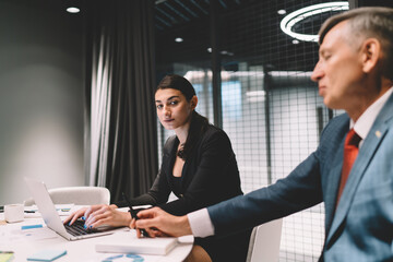 Serious businesswoman browsing laptop during meeting