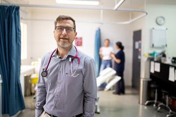 Smiling middle-aged male doctor with a stethoscope around his neck standing in the clinic