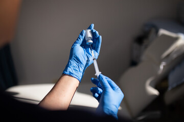 Close up shot of a syringe being inserted to a medicine glass vial by a healthcare worker