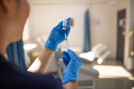 Close up shot of a syringe being inserted to a medicine glass vial by a healthcare worker