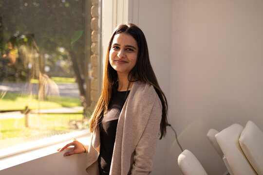 smiling young indian woman by the window