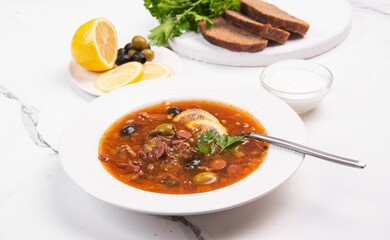 Solyanka in a white plate. Soup with tomatoes and vegetables.