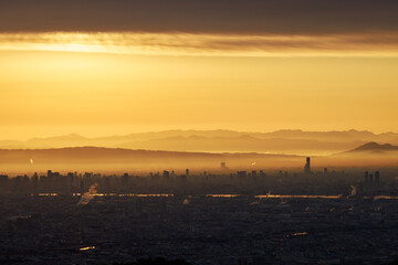 Fototapeta na wymiar Atmospheric haze creates warm orange glow over city at sunrise