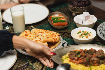 Cropped view of muslim woman putting tasty food on table during ramadan dinner.