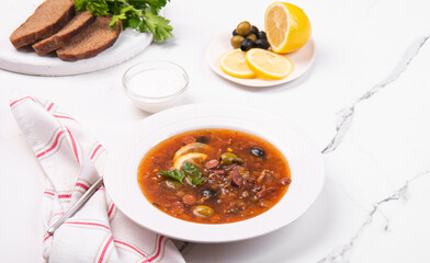 Solyanka in a white plate. Soup with tomatoes and vegetables.