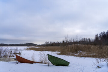 Boats on the shore of a frozen lake in Finland. Winter landscape, copy space.