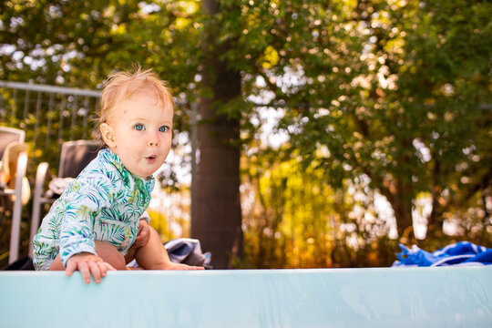 Baby with ooh face excited at the edge of a inground pool