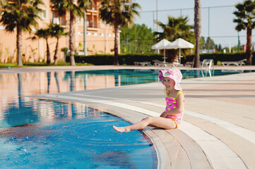 Naklejka premium Smiling cute little girl in pool in sunny day