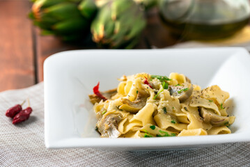 Piatto di deliziose pappardelle condite con carciofi e peperoncino, pasta italiana 