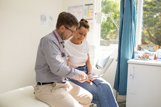Male doctor holding a tablet  and talking to a female patient in the clinic