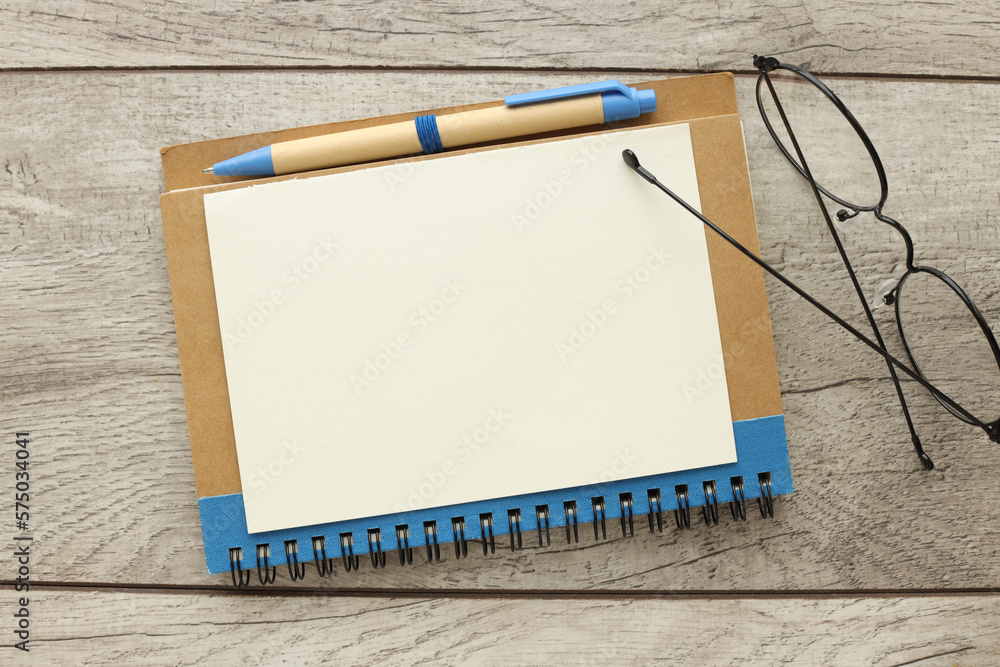 Poster blank notepad is open on a wooden desktop. view from above.