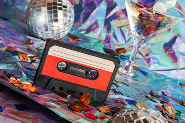 old cassette tape, disco ball and cocktail glass on crumpled neon background.retro and nostalgia...