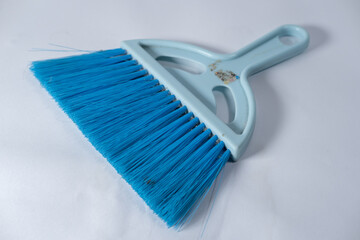 A small blue broom with tight bristles can be used to clean dust or dirt. isolated white background