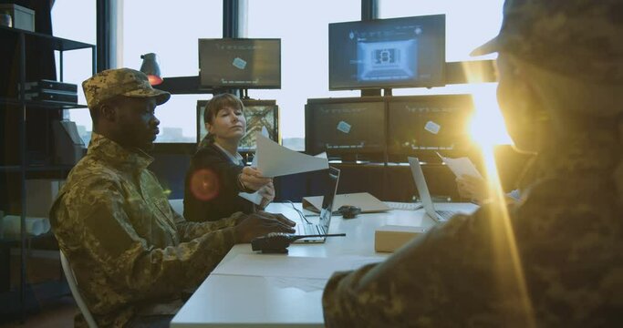 Florida, USA, 2.02.2020: Meeting of military male and female people who deciding serious issues of army. Woman handing secrets documents to men and women in uniforms whos itting round the table.