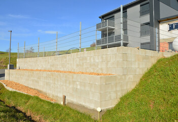 Terrassierte Mauer aus Betonsteinen mit gemulchter Pflanzebene für die Gehölzpflanzung zur...