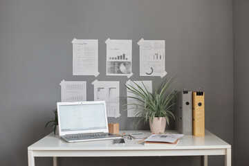 Stylish workspace with desktop computer, office supplies, houseplant and paper folders at office.