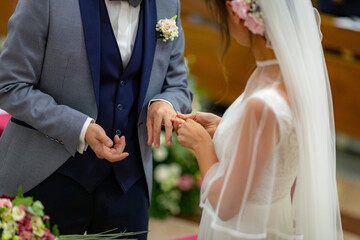 Bride puts her wedding ring on her groom on their wedding day