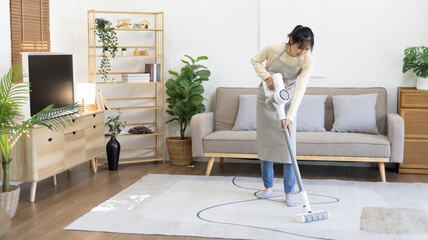Beautiful woman vacuuming the floor and carpet in her living room, Big cleaning in the house, Removes germs, Housewife cleaning, Keeping her home clean, Domestic hygiene.