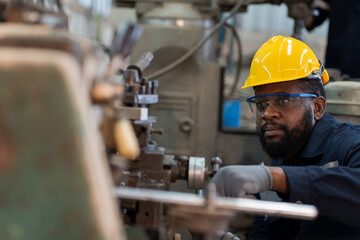 Male factory worker working or maintenance with the machine in the industrial factory while wearing safety uniform and hard hat