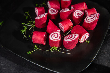Thin red pancakes. Rolls of beetroot pancakes with cream cheese