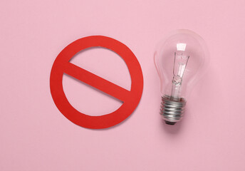 Incandescent light bulb with a prohibition sign on a pink background. Eco concept