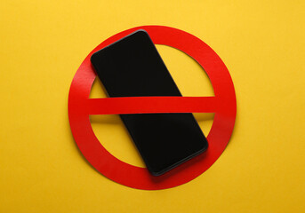 Smartphone with red prohibition sign on yellow background. Ban