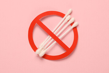 Cotton ear buds with a prohibition sign on a pink background