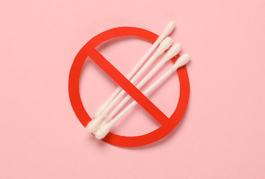 Cotton ear buds with a prohibition sign on a pink background