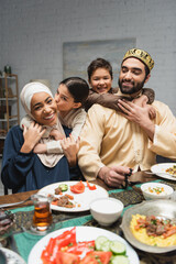 Cheerful middle eastern family hugging near food during ramadan at home.