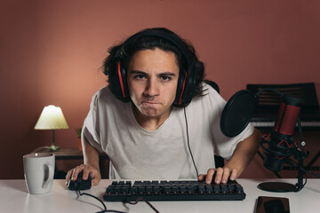 Angry young gamer very focused with a facial expression of concentration in his bedroom 