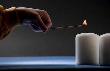 candles with little child's hand, yellow and blue colors, black background