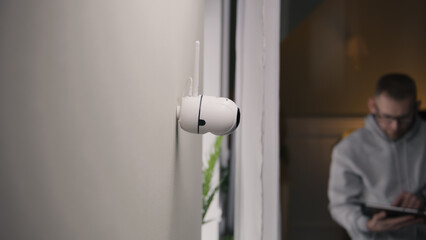 Man sets up security camera at home for the night. He turns on night vision on CCTV camera using digital tablet and application. Concept of tracking system, safety and personal privacy.