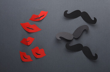 Paper-cut female red lips and male black mustache on a dark background. Flat lay