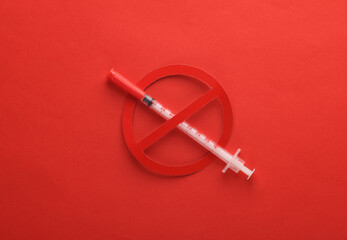 Syringe with prohibition sign on red background