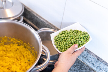 A woman's hand placing peas in the fanesca soup